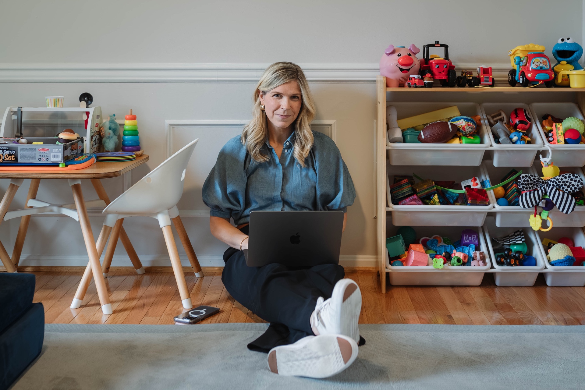 Carole, founder of Clovie, working on a laptop on the floor of her kids' playroom